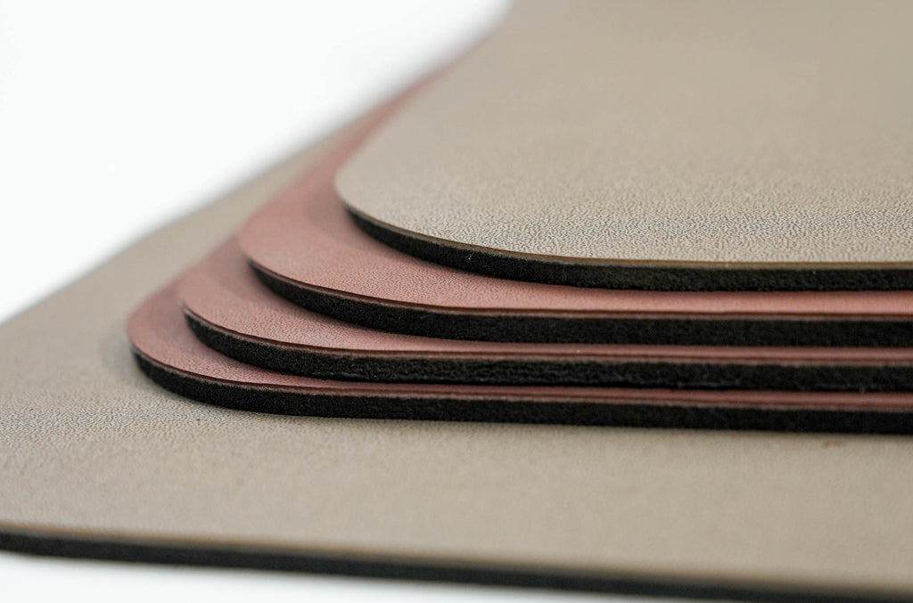 A close-up stack of textured rectangular mats or pads in warm taupe, dusty rose, and dark brown tones, photographed on a clean white background. 4.5mm thick mat cushion.