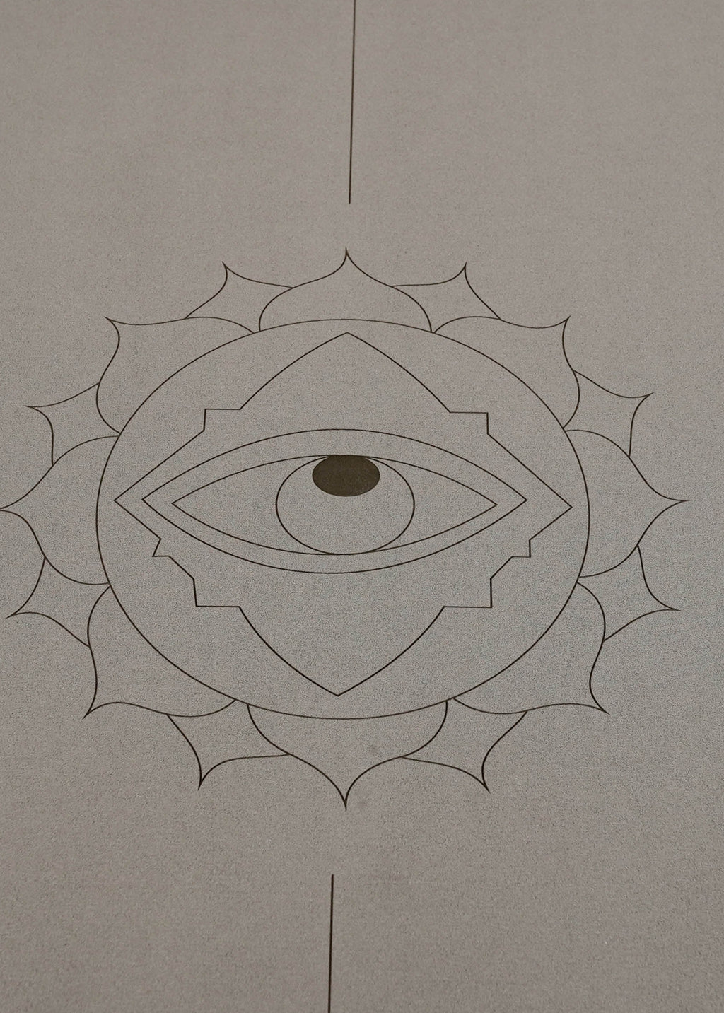 A minimalist yoga mat in a warm taupe-gray color called Eclipse Shadow, featuring a black line-art design of a lotus flower enclosing an eye, with vertical centerlines extending to the top and bottom edges, called Throat Eye shown on a white background.