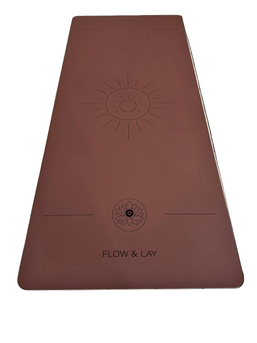 A red rocks Sedona colored extra wide yoga mat with engraved sun design and the text 'FLOW & LAY' at the bottom